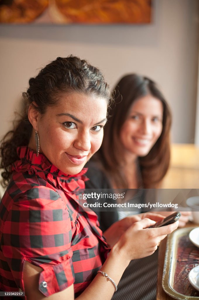 Woman using cell phone in cafe