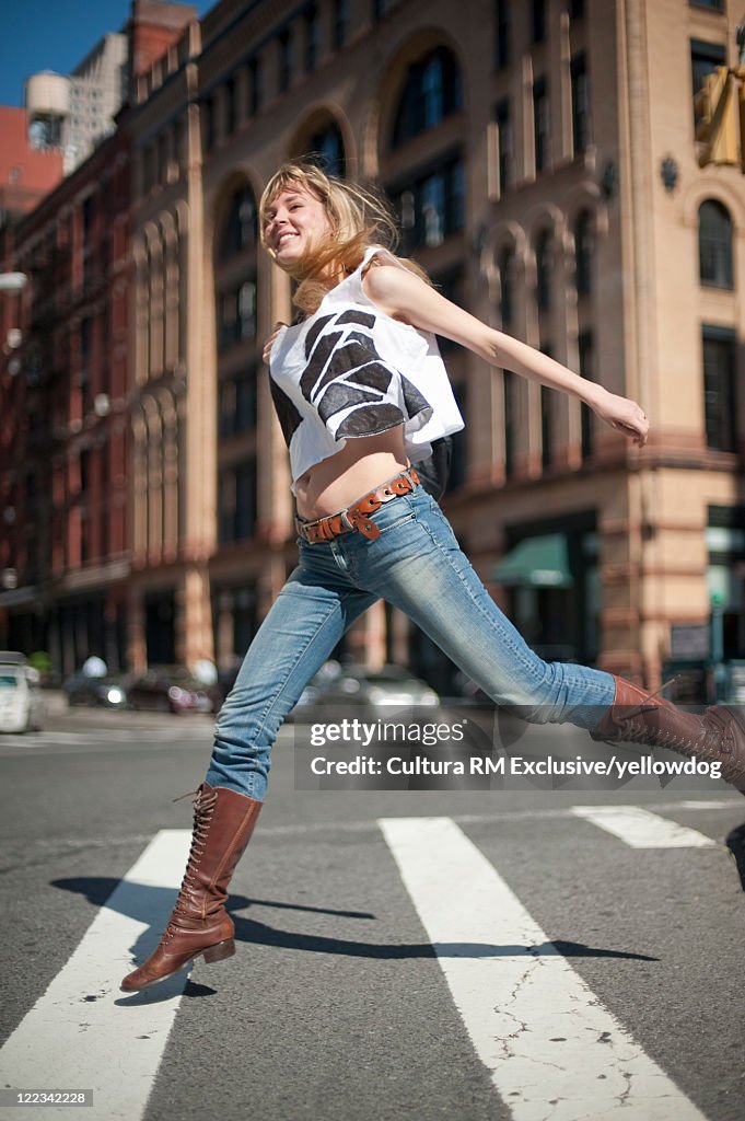 Woman joyfully crossing city street