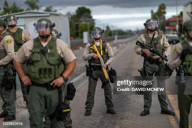 Sheriff's deputies stand guard as activists and relatives of Andres Guardado, who was shot and killed by a sheriff's deputy in Gardena, rally to call...