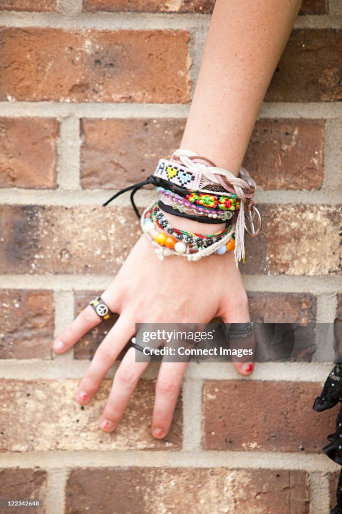 Woman's hand with bracelets by brick wall