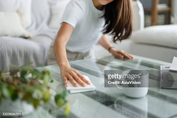 recortado tiro de joven mujer asiática ordenando la sala de estar y limpiando la superficie de la mesa de café con un paño - disinfection fotografías e imágenes de stock
