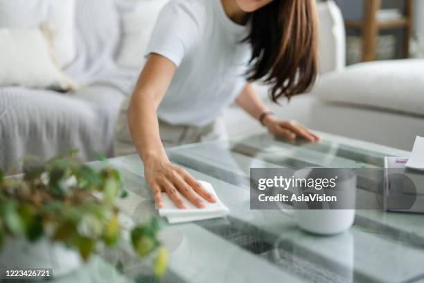 cropped shot of young asian woman tidying up the living room and wiping the coffee table surface with a cloth - disinfecting wipes stock pictures, royalty-free photos & images