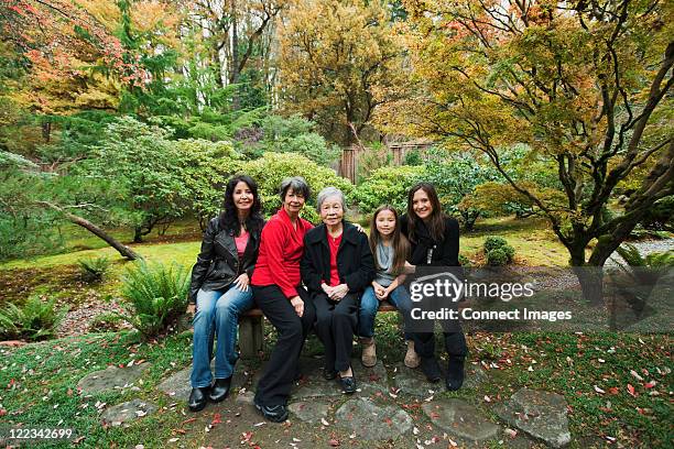 multi generation family sitting in park - great grandmother stock pictures, royalty-free photos & images