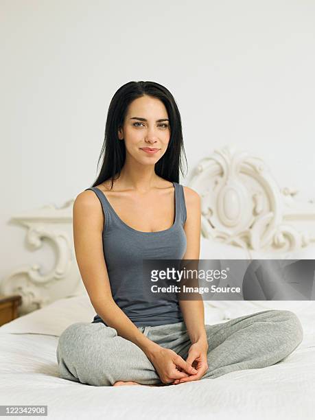 young woman sitting cross legged on bed, portrait - jogging pants stock pictures, royalty-free photos & images