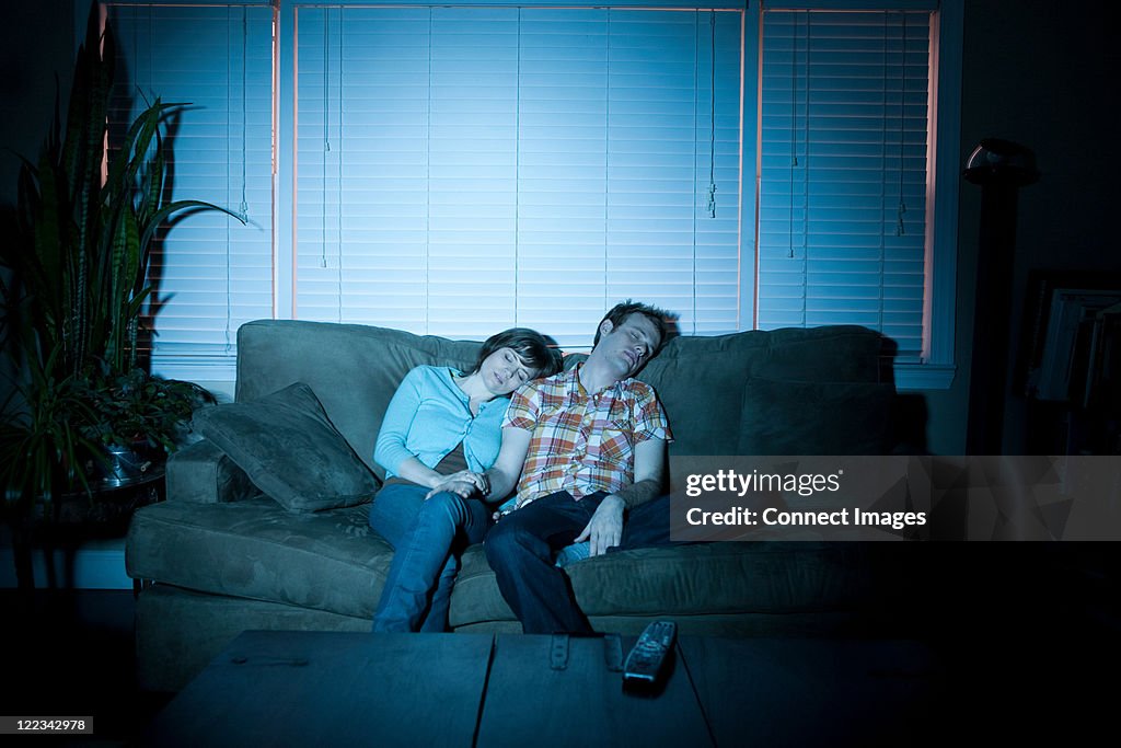 Young couple fallen asleep in front of tv