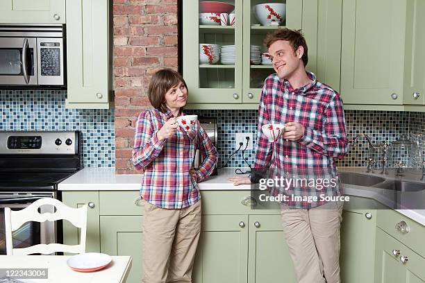 young couple holding teacups in kitchen - copycat stock pictures, royalty-free photos & images