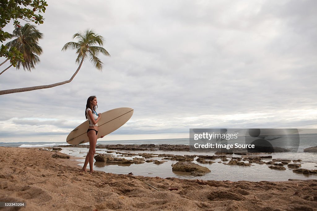 Young woman holding surfboard, portrait