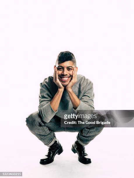 happy young man crouching on white background - hombre agachado fotografías e imágenes de stock