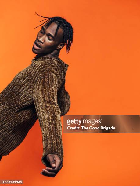 young man falling backwards in studio - fashion orange colour stock pictures, royalty-free photos & images