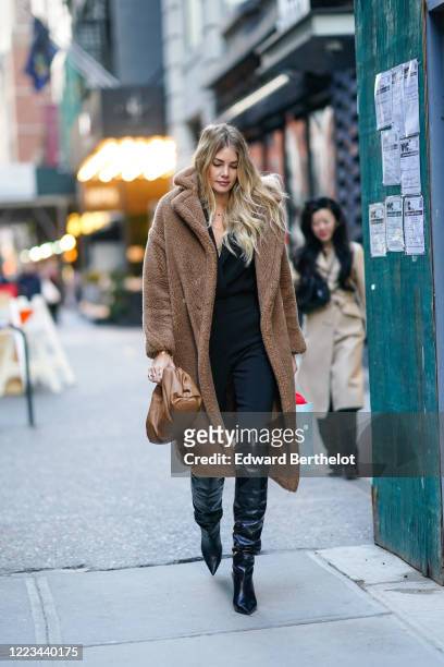 Guest wears a brown long fluffy coat, a brown leather Bottega Veneta Pouch bag, black leather thigh high pointy boots, pants, a black top, outside...