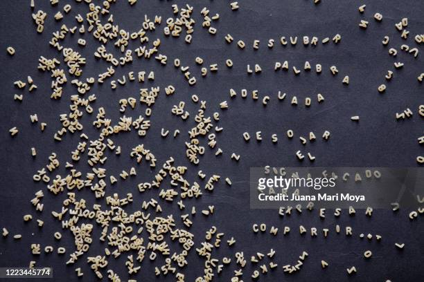 pasta for soup.  in the shape of letters.  write a text in spanish, referring to the words - rechtschreibung stock-fotos und bilder
