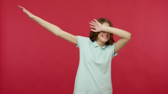 Happy joyful young woman in polo t-shirt celebrating success with dab dance move, famous internet meme