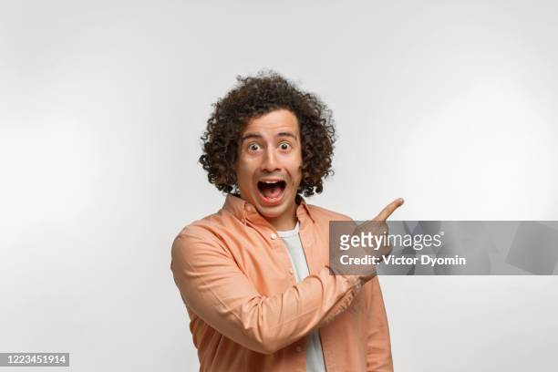 emotional portrait of a curly guy with brown hair - man pointing stock pictures, royalty-free photos & images