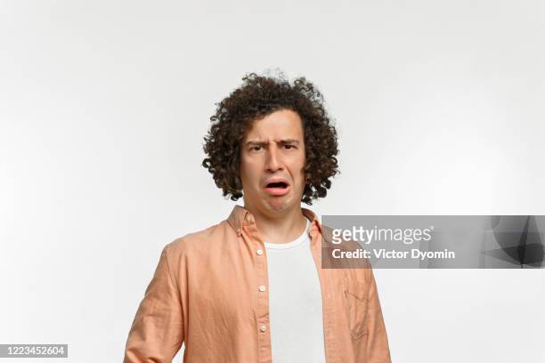 emotional portrait of a curly guy with brown hair - offensive stockfoto's en -beelden