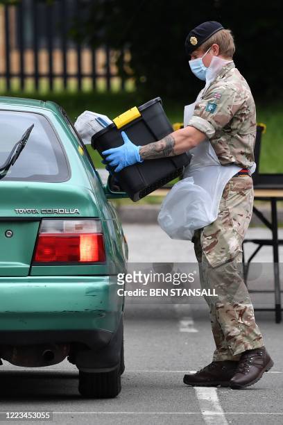 Member of military personnel uses a tub to collect used a self-test kit from a member of the public at a COVID-19 drive-through mobile testing unit...