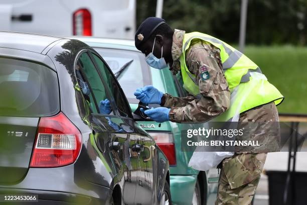 Member of military personnel takes details from members of the public as they staff a COVID-19 drive-through mobile testing unit set up at Evington...