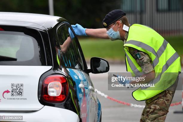 Member of military personnel takes details from members of the public as they staff a COVID-19 drive-through mobile testing unit set up at Evington...