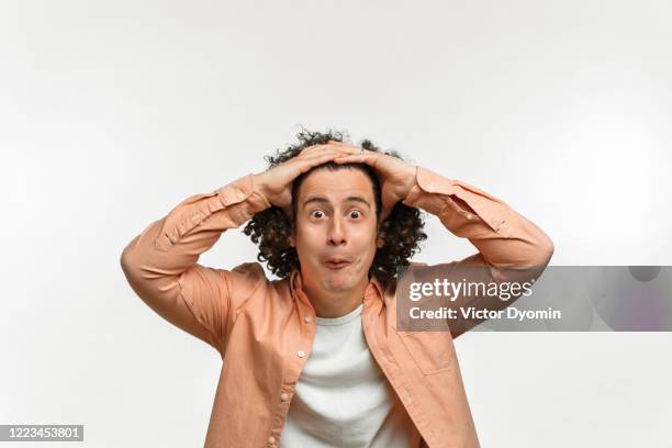 emotional portrait of a curly guy with brown hair - wow face man fotografías e imágenes de stock