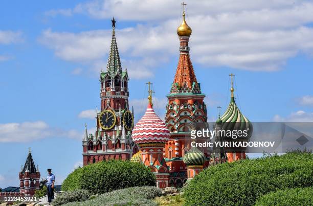 Police officer patrols at the Zaryadye park with the Kremlin's Spasskaya tower and St. Basil's Cathedral on the background in central Moscow on June...
