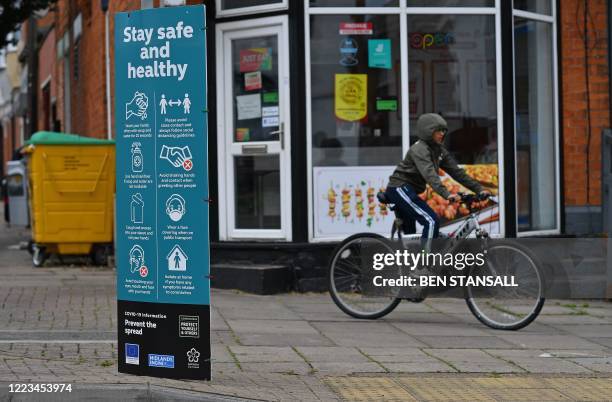 Youth cycles past a sign telling local residents to "Social Distance" and advising on how to help "Prevent the Spread" of coronavirus, in the North...