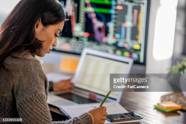 young business woman day trading from her dining room table - finance and economy imagens e fotografias de stock