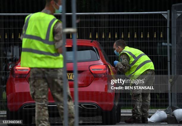 Member of Britain's armed forces helps a member of the public at a mobile COVID-19 testing centre, at Victoria Park in Leicester, central England, on...