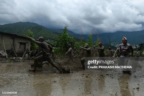 Mud-covered farmers play in a rice paddy field during "National Paddy Day", which marks the start of the annual rice planting season, in Tokha...