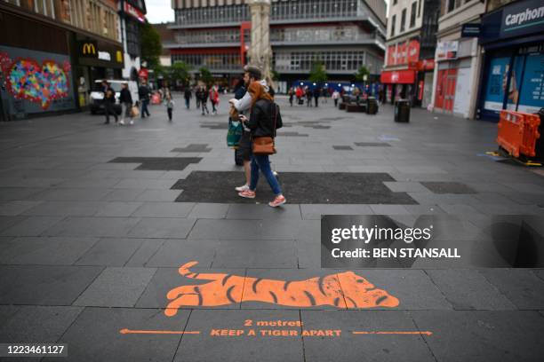 Sign painted on the ground reminds people to practice social distancing as a precaution against the spread of COVID-19 in the centre of Leicester,...