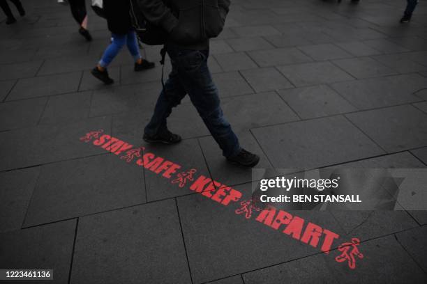 Pedestrian walks past a stencilled message reminding people to practice social distancing as a precaution against the spread of COVID-19 in the...