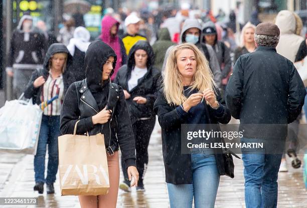 Shoppers carry their purchases in shopping bags as they walk in the rain on Princes Street in Edinburgh on June 29, 2020 as some non-essential shops...