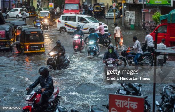 People commute on a rainy evening from waterlogged area at Narpatgiri Chowk, Mangalwar Peth on June 29, 2020 in Pune, India.