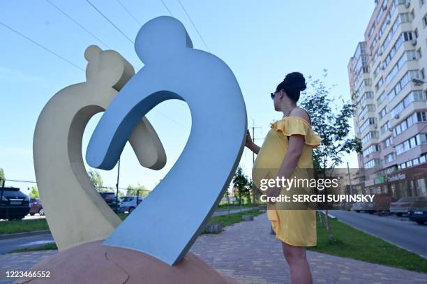 In this photograph taken on June 12 Olga, a 26-year-old going through her second surrogacy and expecting twins for a Chinese couple, holds her belly...