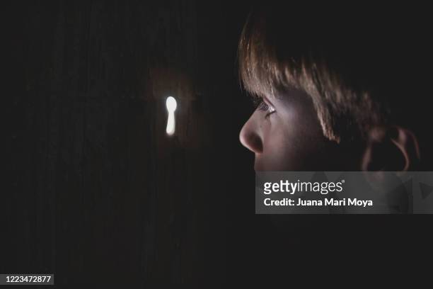 close-up of a boy looking through a keyhole.  idyllic, fairy-tale-like image - se cacher photos et images de collection