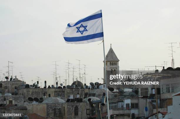 An Israeli flag waves in the wind atop the roof of Wittenberg House an apartment complex in the Muslim quarter of Jerusalem's old city on October 5,...