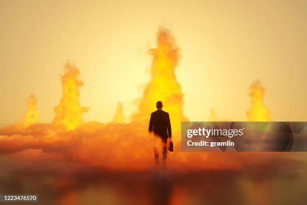 uomo d'affari che cammina tra le esplosioni - inferno foto e immagini stock