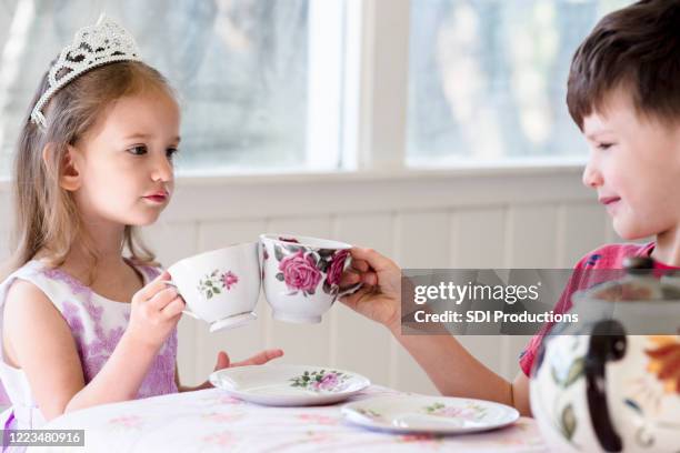 sister and brother clink teacups together while playing - boy tiara stock pictures, royalty-free photos & images