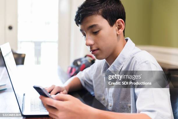 teenager uses smartphone while working on homework assignment - junior high student stock pictures, royalty-free photos & images