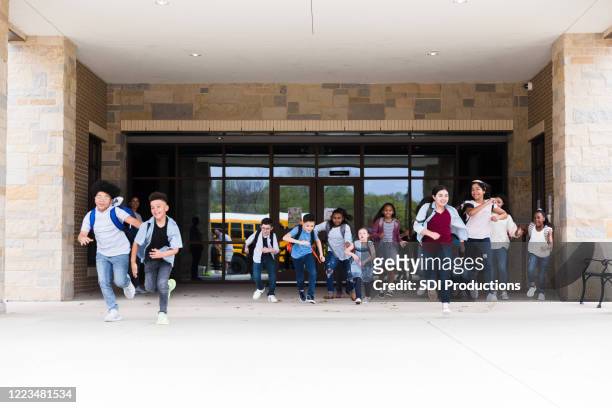 excited schoolchildren leave school building - last day of school stock pictures, royalty-free photos & images