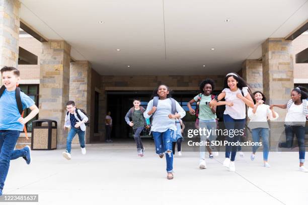 diverse students race toward bus after school - public school building stock pictures, royalty-free photos & images