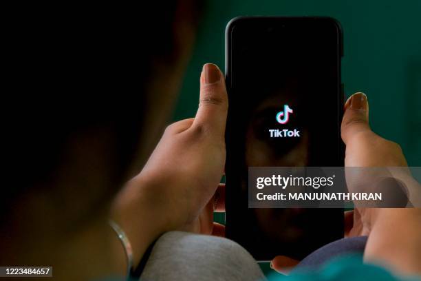 An Indian mobile user browses through the Chinese owned video-sharing 'Tik Tok' app on a smartphone in Bangalore on June 30, 2020. - TikTok on June...