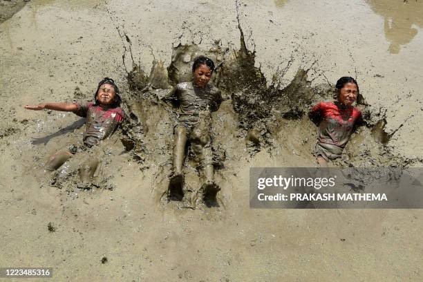 In this photograph taken on June 29, 2020 children play in a rice paddy field during "National Paddy Day", which marks the start of the annual rice...