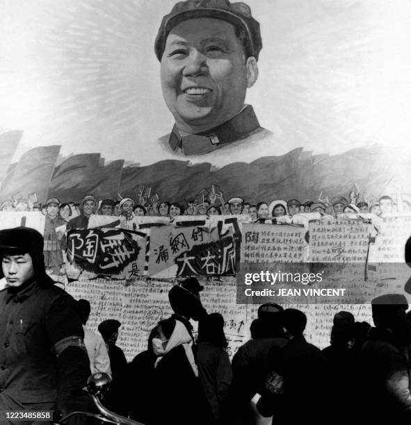 Chinese people including red guards read dazibaos under a a huge poster showing Chairman Mao Zedong in Beijing in January 1967 during the "great...