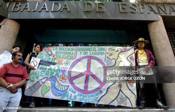 Member of the group "Committee against the War" holds a banner bearing a peace sign during a protest against Spain's support of a US-led attack on...