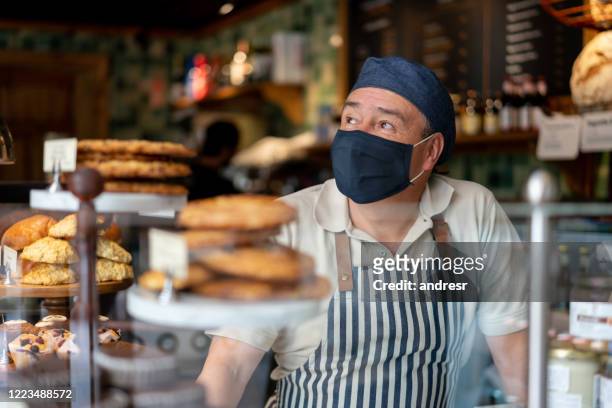 mann arbeitet in einem café mit gesichtsmaske - essenzielle berufe und dienstleistungen stock-fotos und bilder