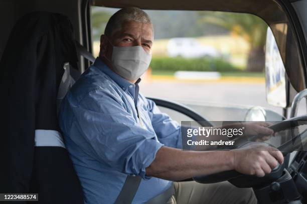 porträt eines lkw-fahrers, der eine gesichtsmaske trägt, um dem coronavirus zu entgehen - essenzielle berufe und dienstleistungen stock-fotos und bilder
