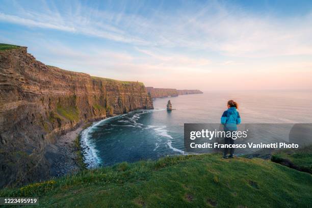 woman at the cliffs of moher, ireland. - ireland photos et images de collection