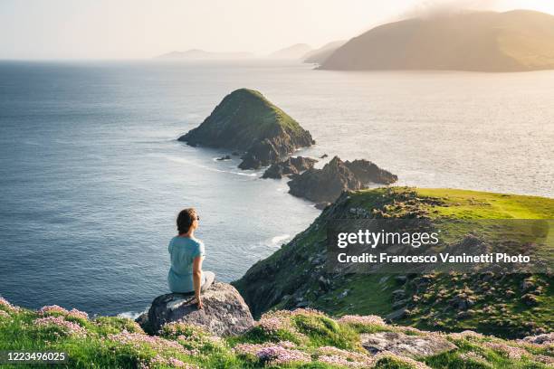 woman at dunmore head gazing at the devil horns, ireland. - verwaltungsbezirk county kerry stock-fotos und bilder