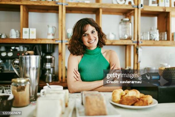 indoor portrait von lächeln weibliche cafe-besitzer hinter counter - mit ellenbogen gestützt stock-fotos und bilder