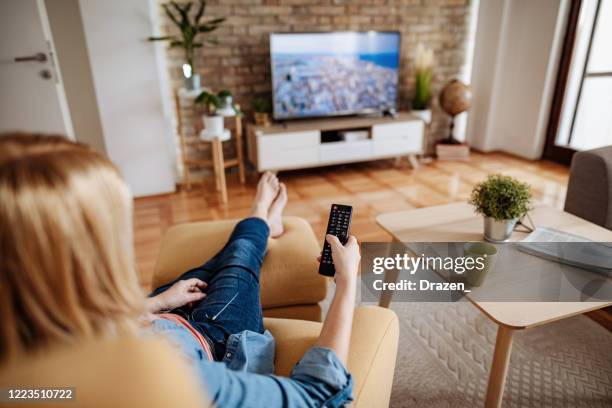 barefoot mature woman relaxing at home and watching tv - news home stock pictures, royalty-free photos & images