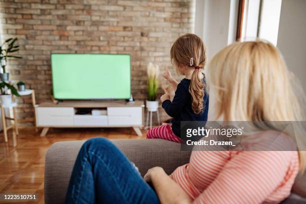 grandmother watching tv at home with 3 year old girl - chroma key screen - cartoon tv stock pictures, royalty-free photos & images
